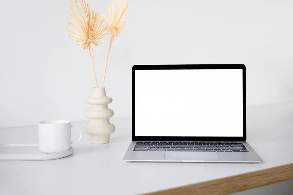 Vue plongeante d’un bureau moderne et épuré, avec un ordinateur portable, une tablette et des accessoires.